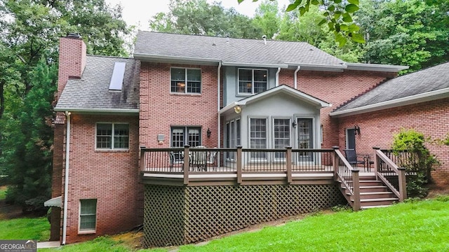 rear view of house featuring a lawn and a wooden deck