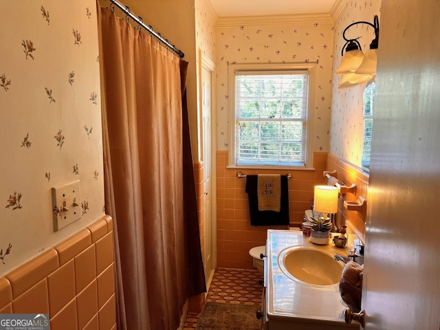 bathroom with tile walls, vanity, walk in shower, toilet, and crown molding