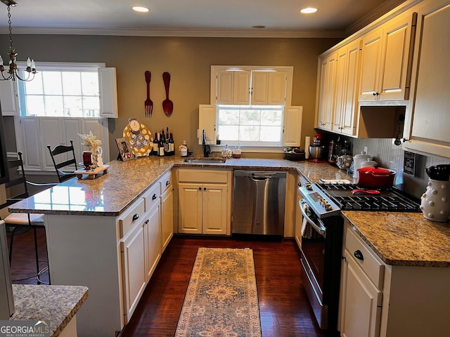 kitchen with appliances with stainless steel finishes, decorative light fixtures, sink, light stone counters, and kitchen peninsula