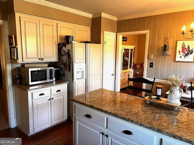 kitchen with dark stone countertops, dark wood-type flooring, ornamental molding, and white cabinets