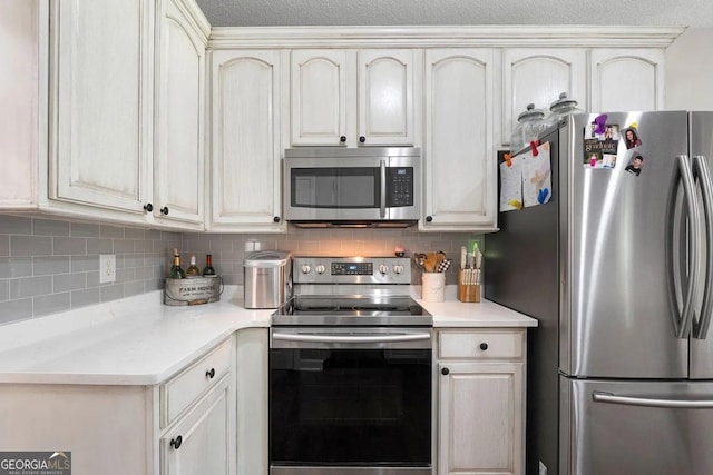 kitchen featuring stainless steel appliances, decorative backsplash, and a textured ceiling