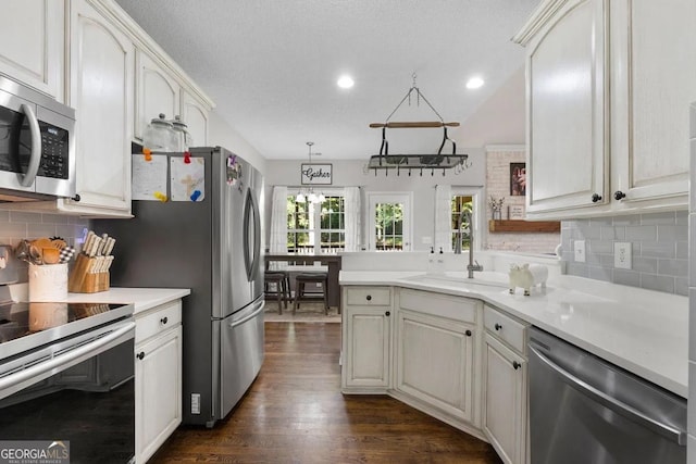 kitchen featuring stainless steel appliances, sink, tasteful backsplash, hanging light fixtures, and dark wood-type flooring