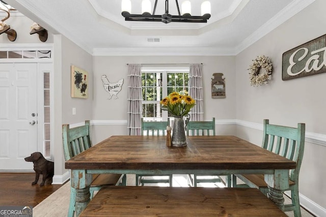 dining room featuring dark hardwood / wood-style flooring, ornamental molding, and a tray ceiling