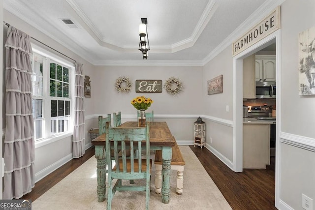 dining area with a tray ceiling, crown molding, and dark hardwood / wood-style floors