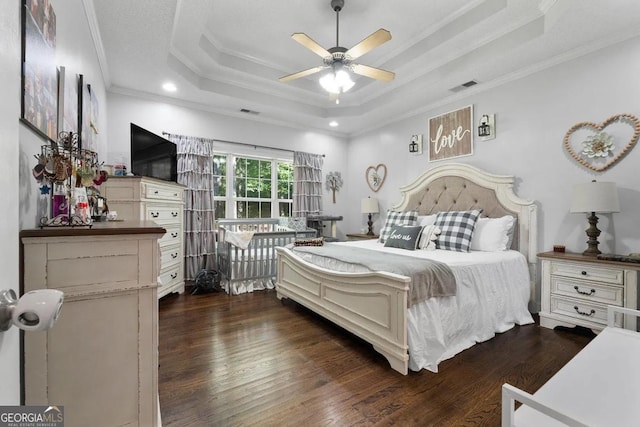 bedroom with ceiling fan, a tray ceiling, crown molding, and dark hardwood / wood-style floors