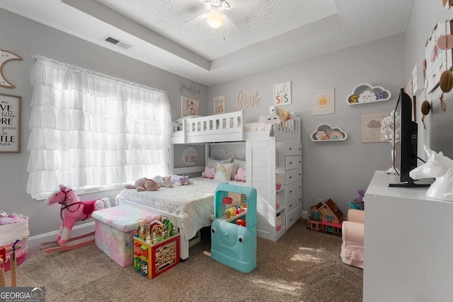 bedroom featuring a raised ceiling, carpet floors, ceiling fan, and multiple windows