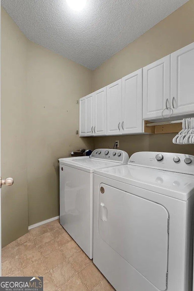 laundry area featuring washer and dryer, cabinets, a textured ceiling, and light tile patterned floors