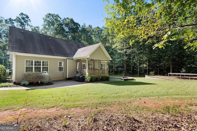 rear view of property featuring a yard, covered porch, and a trampoline