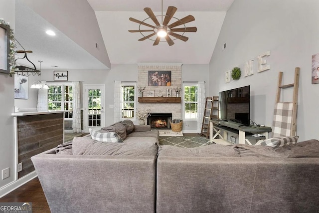 living room featuring ceiling fan, a stone fireplace, high vaulted ceiling, and dark hardwood / wood-style floors