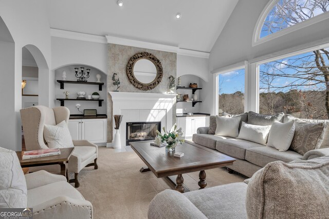 living room with light carpet, ornamental molding, high vaulted ceiling, a fireplace, and built in shelves