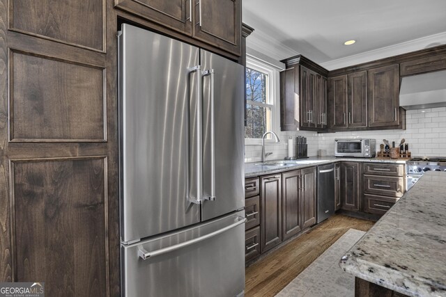 kitchen featuring sink, wall chimney exhaust hood, backsplash, light stone countertops, and premium appliances