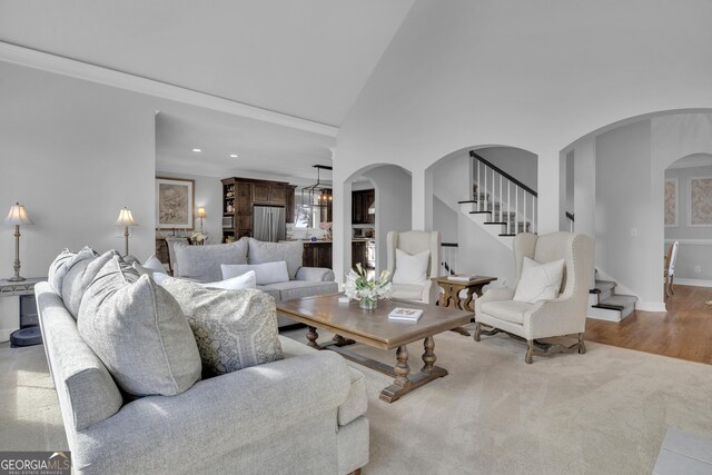 living room with ornamental molding, a notable chandelier, and high vaulted ceiling