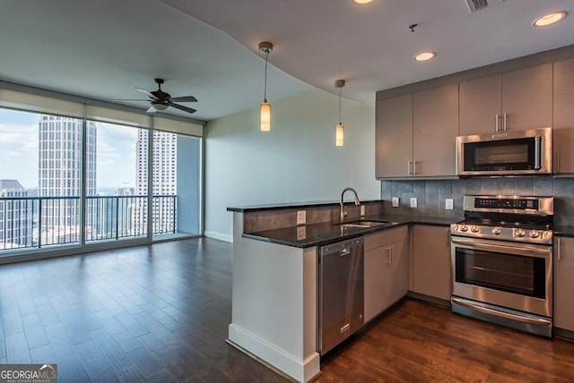 kitchen with stainless steel appliances, kitchen peninsula, sink, and dark stone countertops