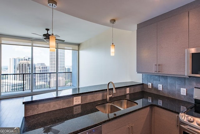 kitchen featuring pendant lighting, sink, appliances with stainless steel finishes, decorative backsplash, and dark stone counters