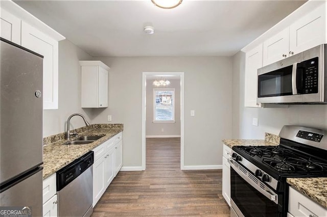 kitchen with appliances with stainless steel finishes, white cabinetry, light stone countertops, and sink