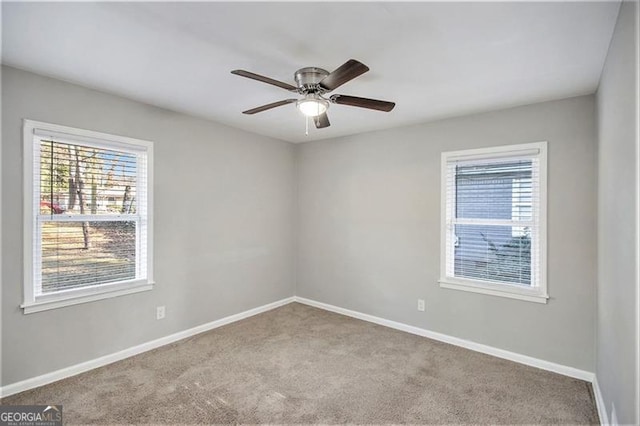 carpeted spare room featuring ceiling fan and a wealth of natural light