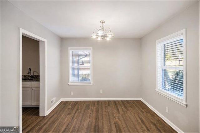 unfurnished room featuring sink, dark hardwood / wood-style flooring, a chandelier, and plenty of natural light