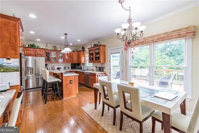 dining room featuring a notable chandelier, light hardwood / wood-style flooring, crown molding, and sink