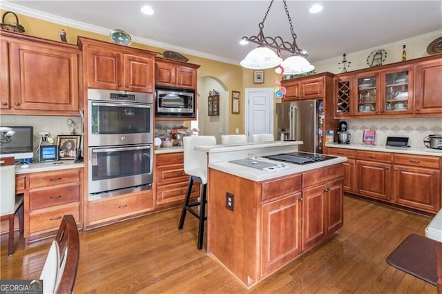 kitchen with stainless steel appliances, a breakfast bar, pendant lighting, a kitchen island, and backsplash