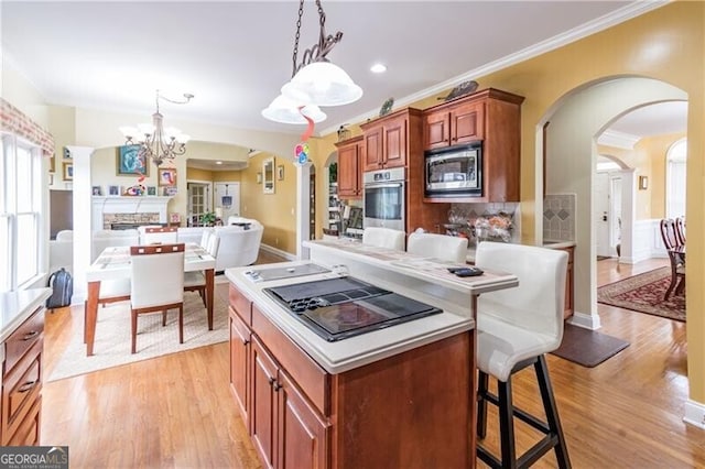 kitchen with a chandelier, hanging light fixtures, stainless steel appliances, a breakfast bar, and ornamental molding