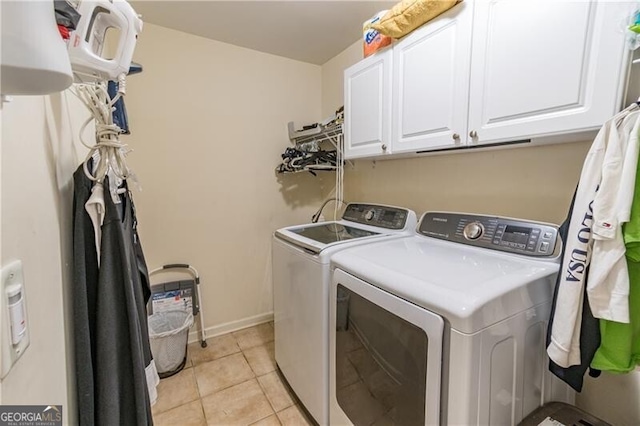 laundry room with cabinets, washing machine and dryer, and light tile patterned floors