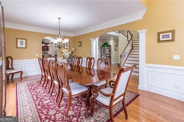 dining space with decorative columns, a notable chandelier, light hardwood / wood-style floors, and ornamental molding