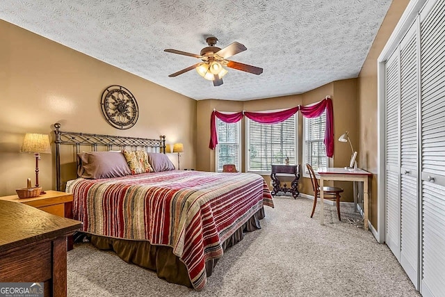 bedroom featuring a textured ceiling, ceiling fan, a closet, and carpet