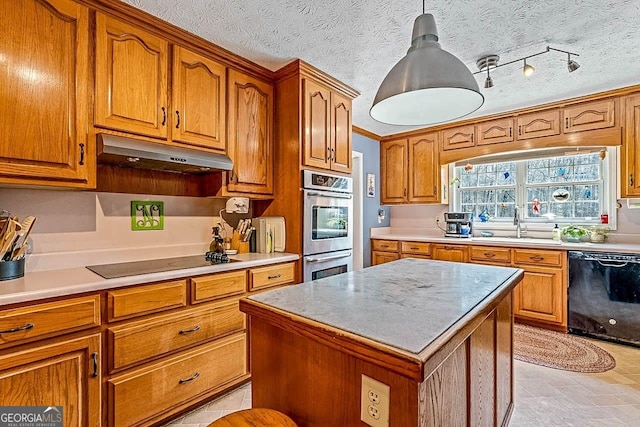 kitchen with a textured ceiling, a center island, black appliances, and pendant lighting