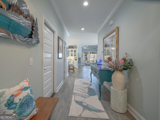 hall with light wood-type flooring and crown molding