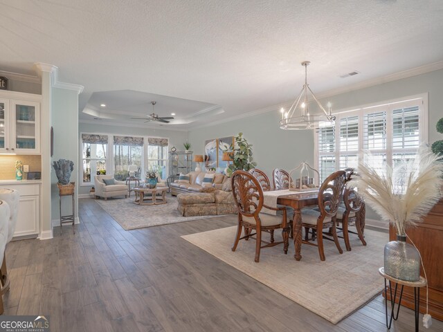 dining space featuring ceiling fan with notable chandelier, a raised ceiling, and crown molding