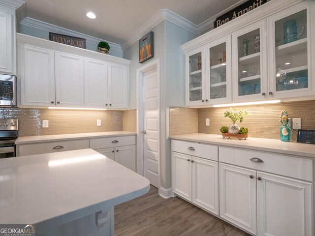 kitchen featuring white cabinets, ornamental molding, tasteful backsplash, and wood-type flooring