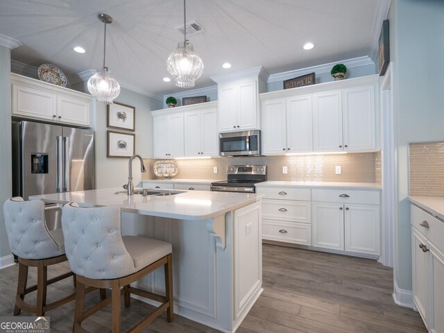 kitchen featuring sink, stainless steel appliances, white cabinets, and hanging light fixtures