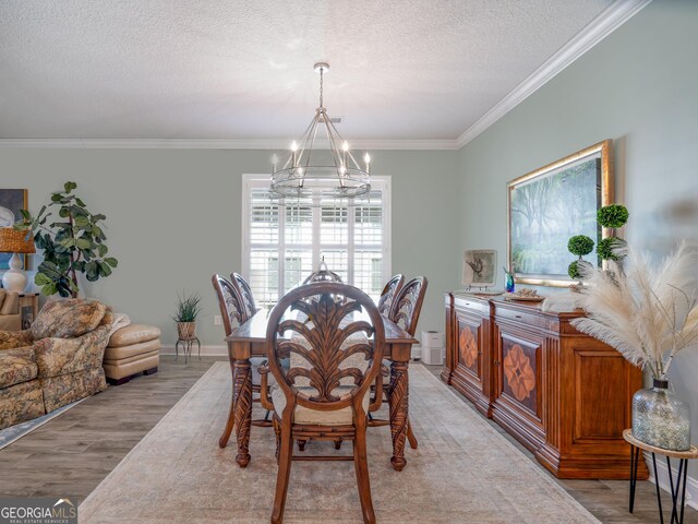 dining area featuring light wood-type flooring, crown molding, a chandelier, and a textured ceiling