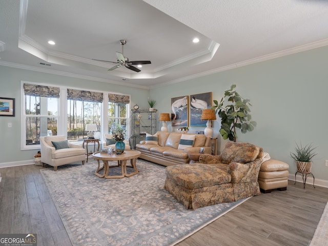 living room featuring ornamental molding, ceiling fan, hardwood / wood-style floors, and a raised ceiling