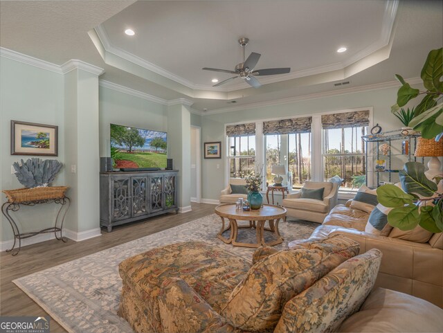 living room with ceiling fan, crown molding, hardwood / wood-style floors, and a raised ceiling