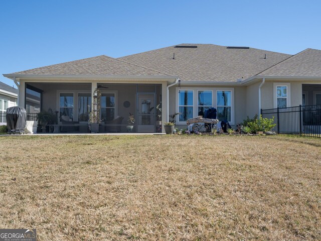 rear view of property featuring a yard and a sunroom