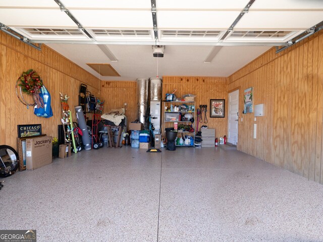 garage with a garage door opener and wooden walls