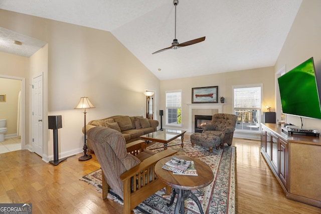 living room with light hardwood / wood-style floors, ceiling fan, high vaulted ceiling, and plenty of natural light