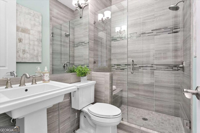 bathroom featuring toilet, a shower with door, and sink