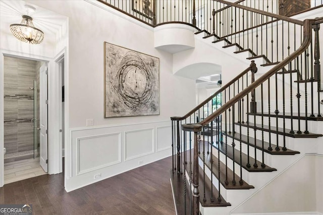 stairs with ceiling fan with notable chandelier and wood-type flooring