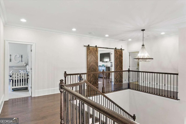 hall with a barn door, crown molding, and hardwood / wood-style floors