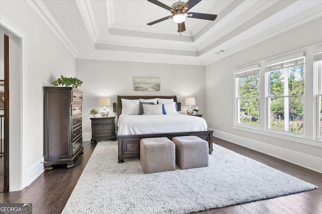 bedroom featuring ceiling fan, a tray ceiling, crown molding, and dark hardwood / wood-style flooring