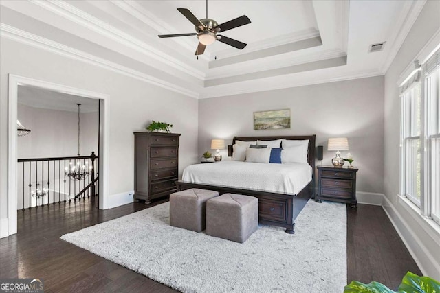 bedroom with dark wood-type flooring, ceiling fan, a tray ceiling, and multiple windows