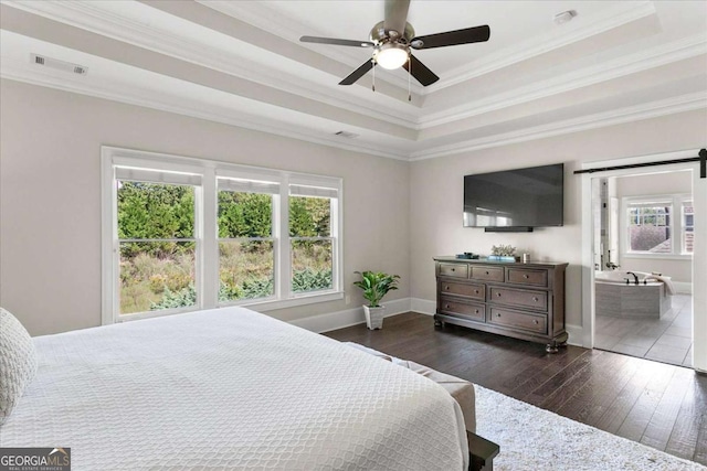 bedroom with a barn door, ceiling fan, dark wood-type flooring, ornamental molding, and a tray ceiling