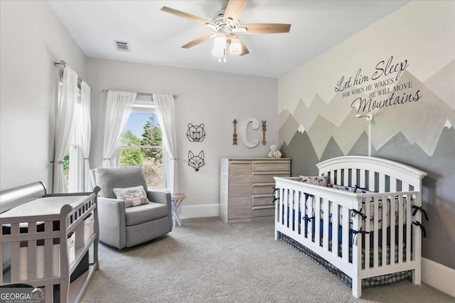 carpeted bedroom with ceiling fan and a crib