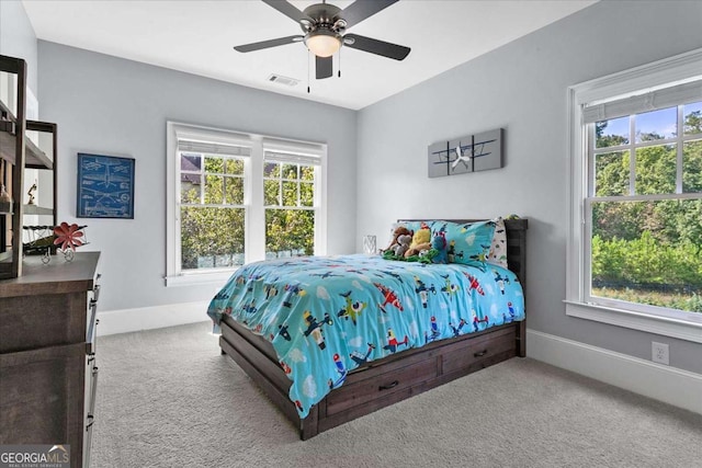 bedroom featuring ceiling fan, multiple windows, and carpet flooring