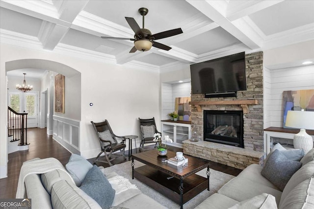 living room with beam ceiling, coffered ceiling, and a stone fireplace