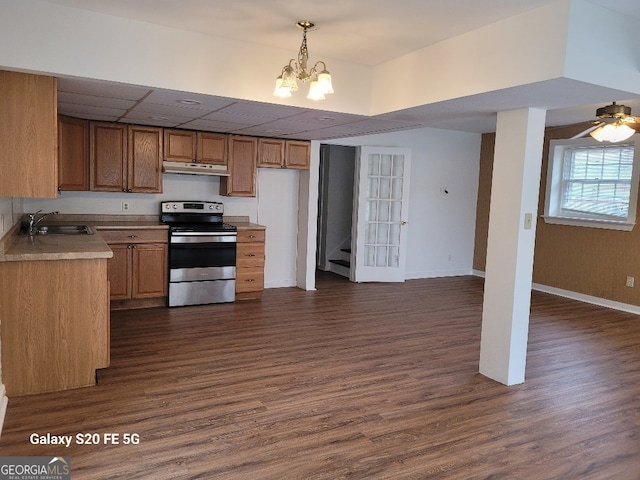 kitchen featuring stainless steel electric range, pendant lighting, dark hardwood / wood-style floors, sink, and ceiling fan with notable chandelier