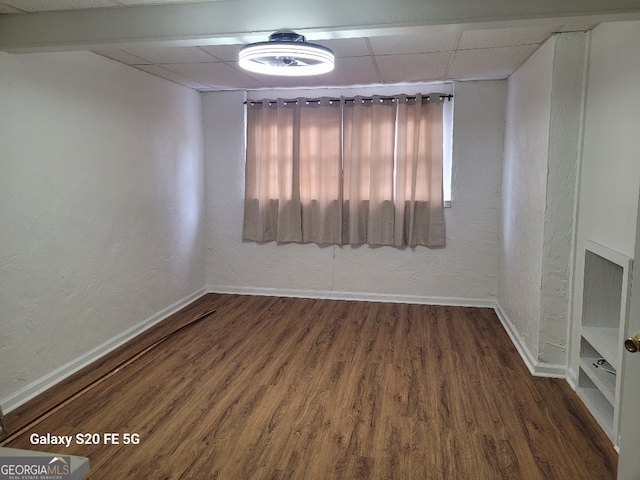 empty room with dark hardwood / wood-style flooring and a paneled ceiling