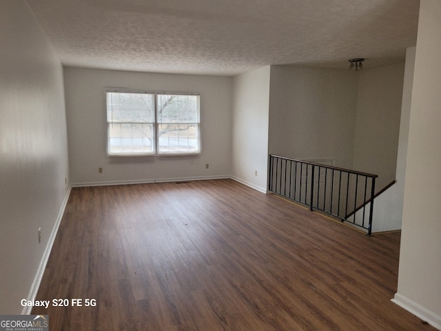 spare room featuring dark hardwood / wood-style flooring and a textured ceiling